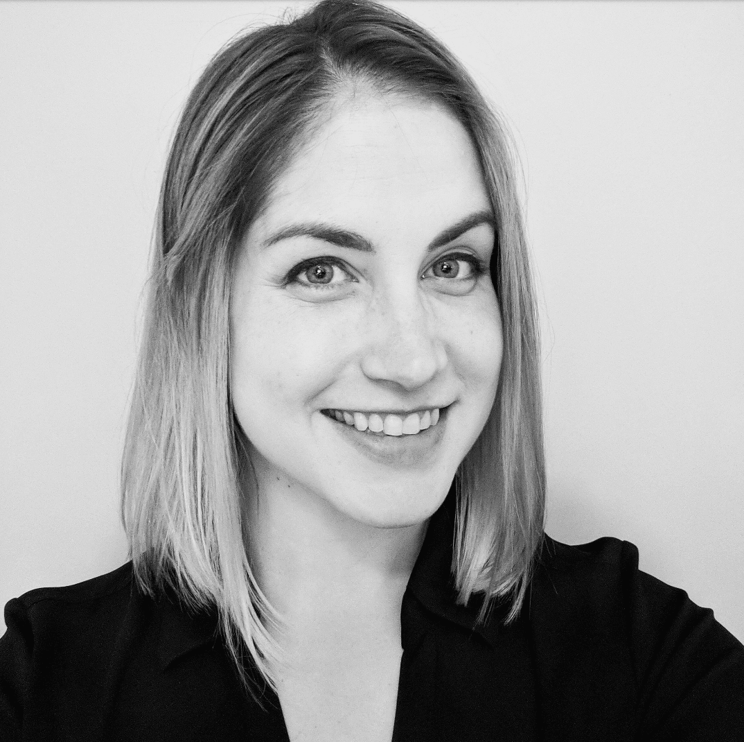 Black and white headshot of a smiling woman with light hair and a blazer.