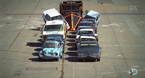 gif of an armored street sweeper pushing cars out of the way