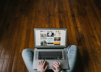 person sitting on hardwood floor with a laptop on their lap