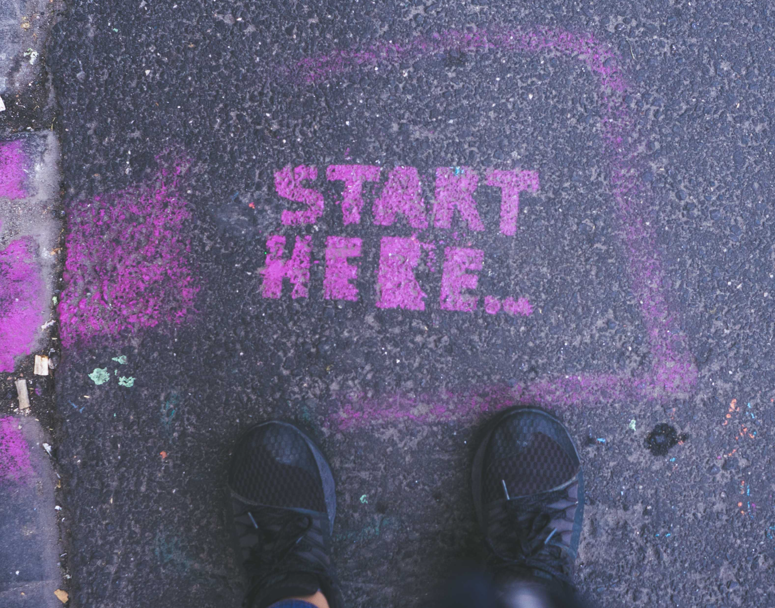 image of concrete with the words "start here" painted in pink